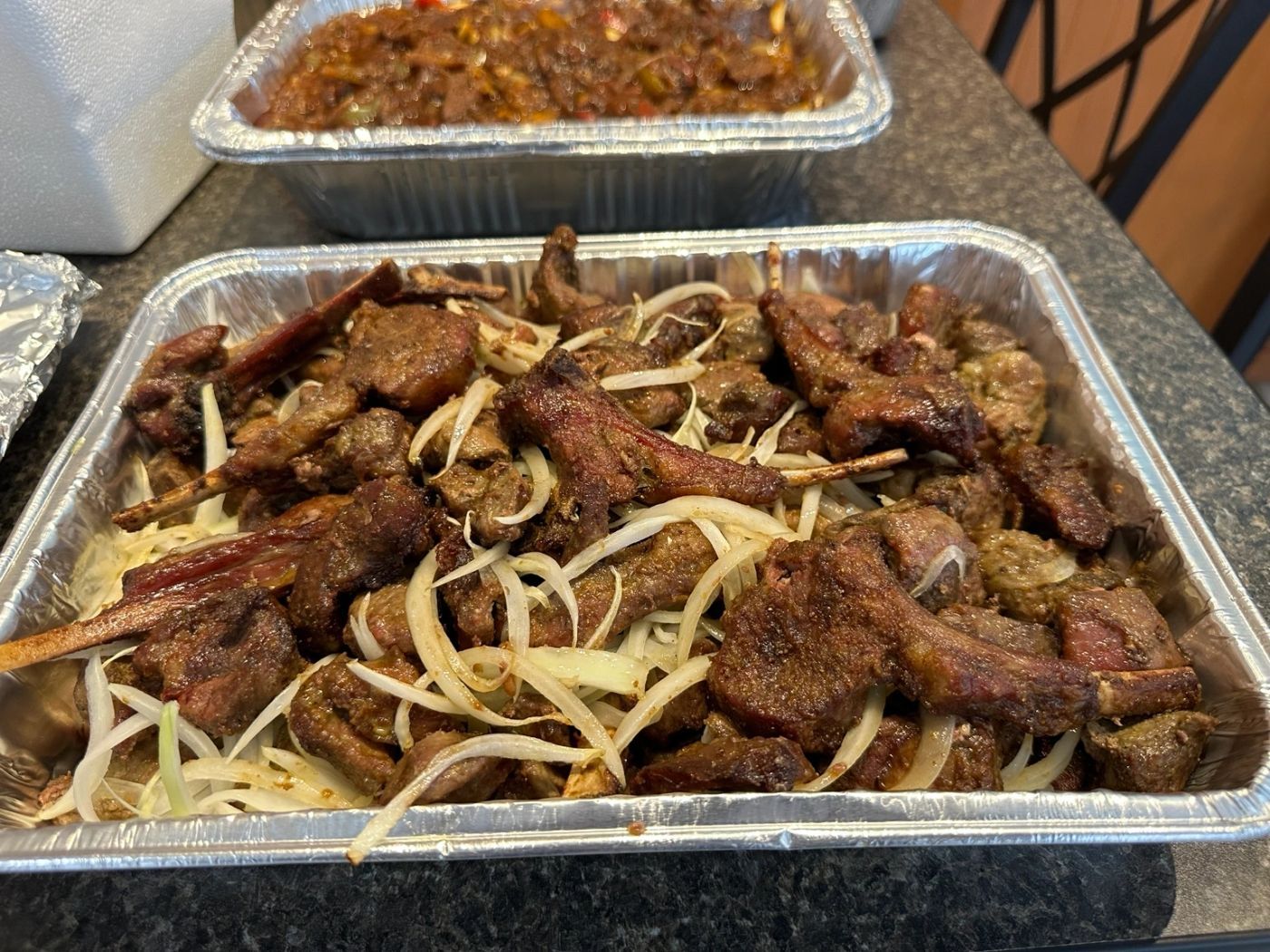 Catering tray of grilled meat with sliced onions